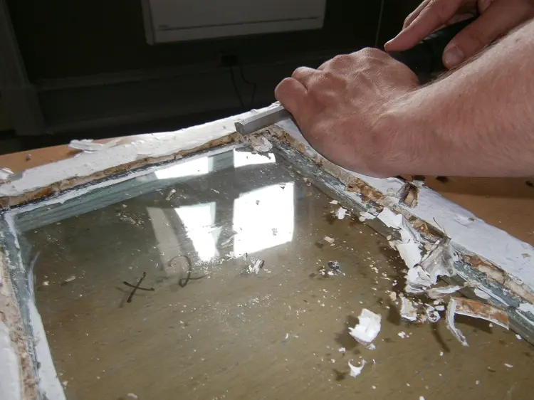 Fjerning av kitt. Det er viktig å skrape forsiktig, gammelt glass kan være sprøtt og det er lett å lage riper. Foto: Byggeskikksenteret