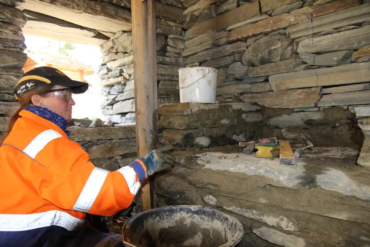 Gerd Gjengedal Aasen spekker fugene i grua med leirmørtel
